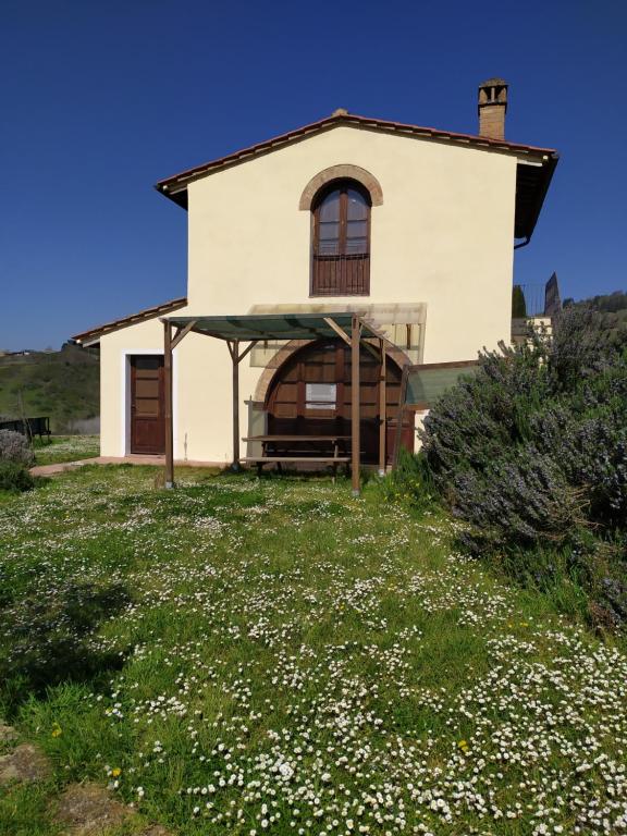 una casa en una colina con un campo de flores en La Casina- Podere della Collina, en Collelungo