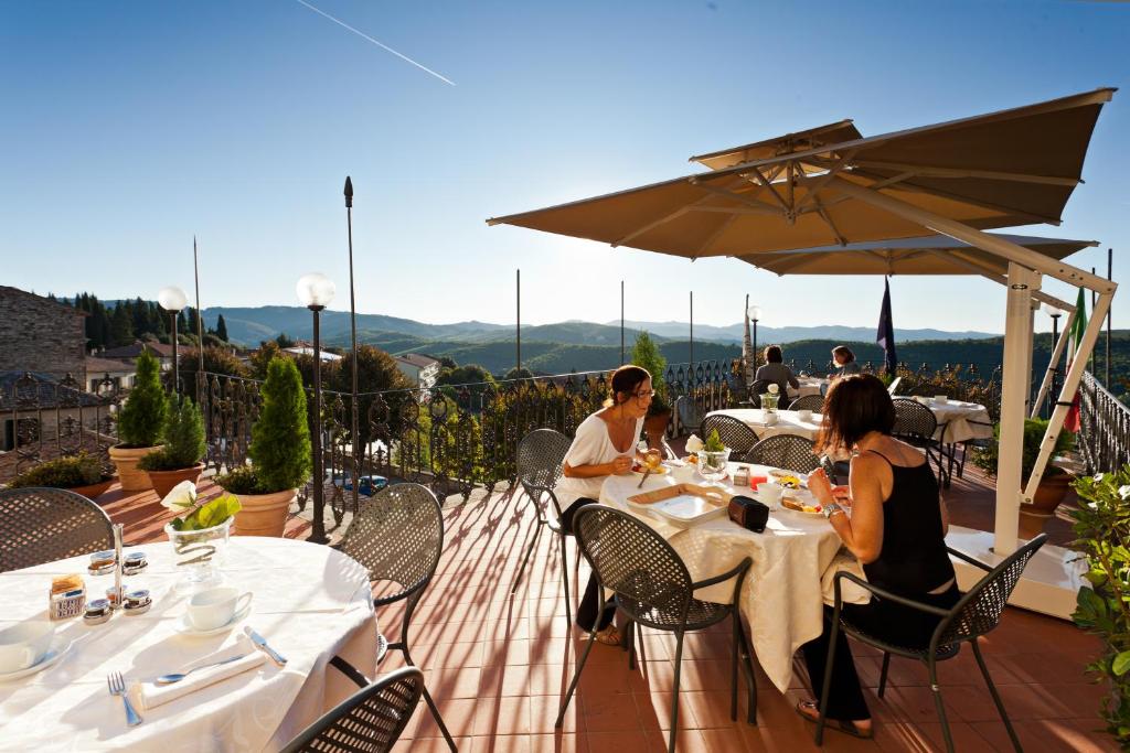 a woman sitting at a table in front of a patio at Palazzo Leopoldo Dimora Storica & Spa in Radda in Chianti