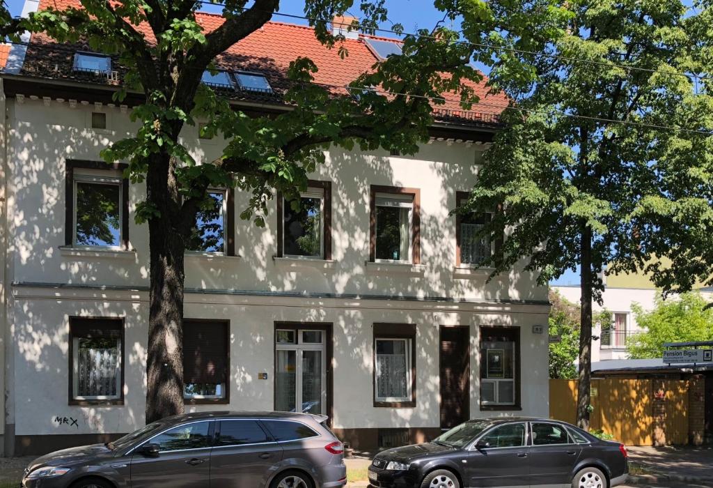 deux voitures garées devant un bâtiment blanc dans l'établissement Bigus, à Berlin