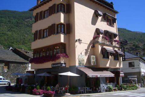 un gran edificio con una sombrilla delante de él en Hostal Montaña, en Alins