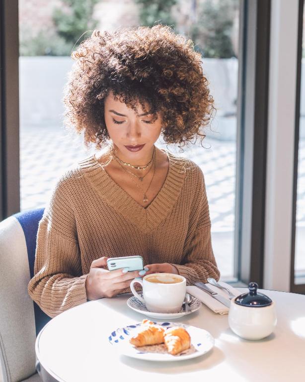 a woman sitting at a table with a cup of coffee at Seventy Barcelona in Barcelona