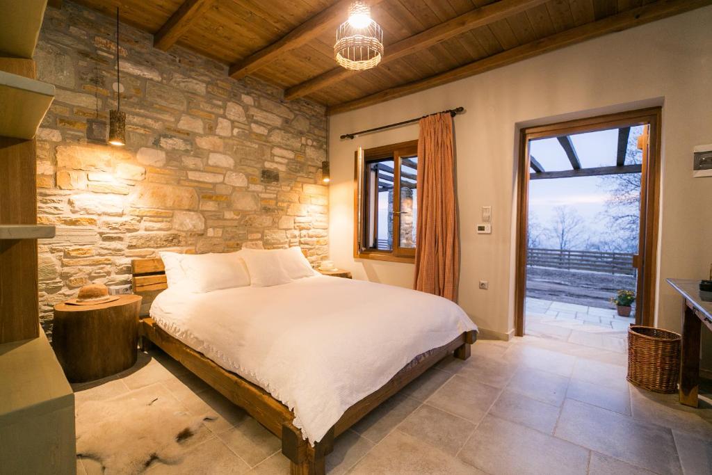 a bedroom with a bed and a stone wall at Farmhouse Karaiskos in Portaria