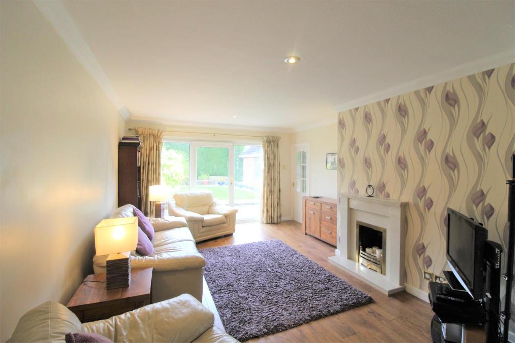 a living room with a couch and a fireplace at Spacious bungalow/private garden-sleeps up to 6 in Marple