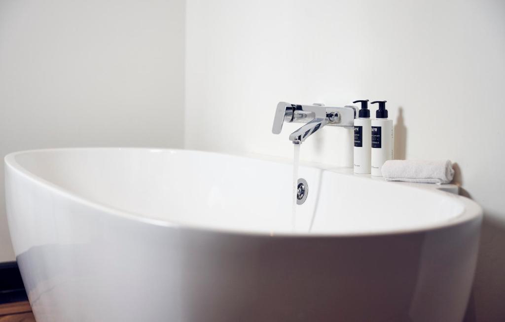 a bathroom with a white tub and a sink at Hotel New York by WestCord in Rotterdam
