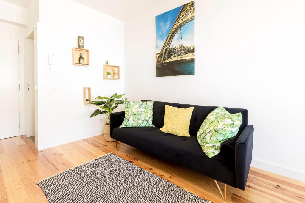 uma sala de estar com um sofá preto com almofadas amarelas em Guest H4U - Porto Batalha City Center no Porto