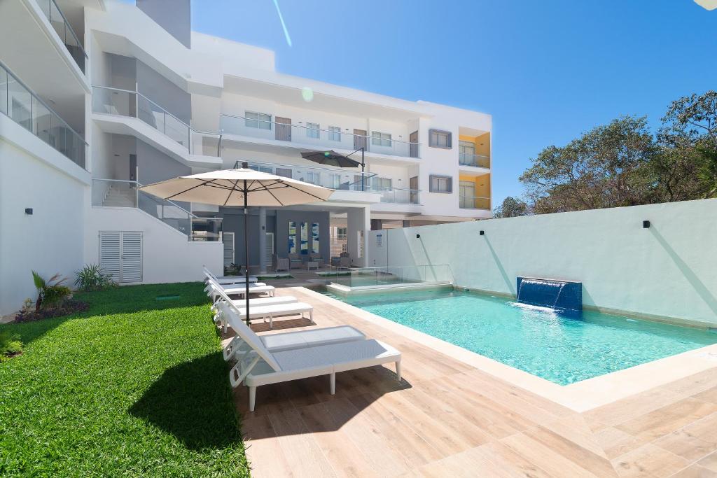 uma piscina com cadeiras e um guarda-sol ao lado de um edifício em Heaven Hotel em Playa del Carmen