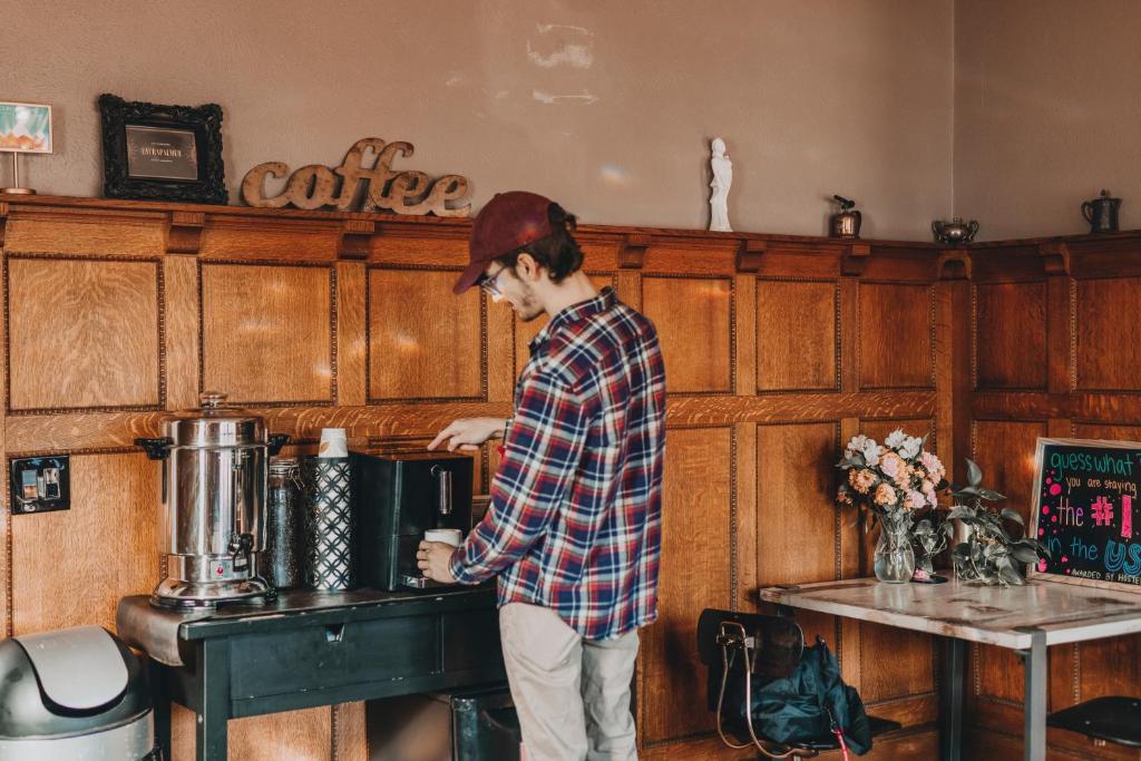 a man standing in a coffee shop with a cup of coffee at Ember Hostel in Denver