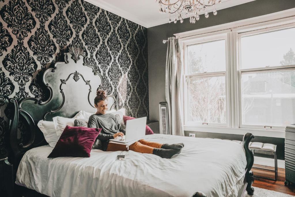 a woman sitting on a bed with a laptop at Ember Hostel in Denver