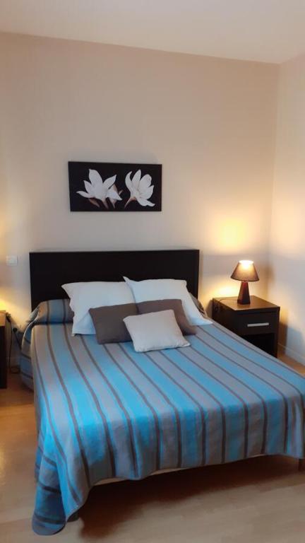 a bedroom with a large bed with a blue blanket at HOTEL Restaurant LE CALDERO in Montpon-Ménestérol