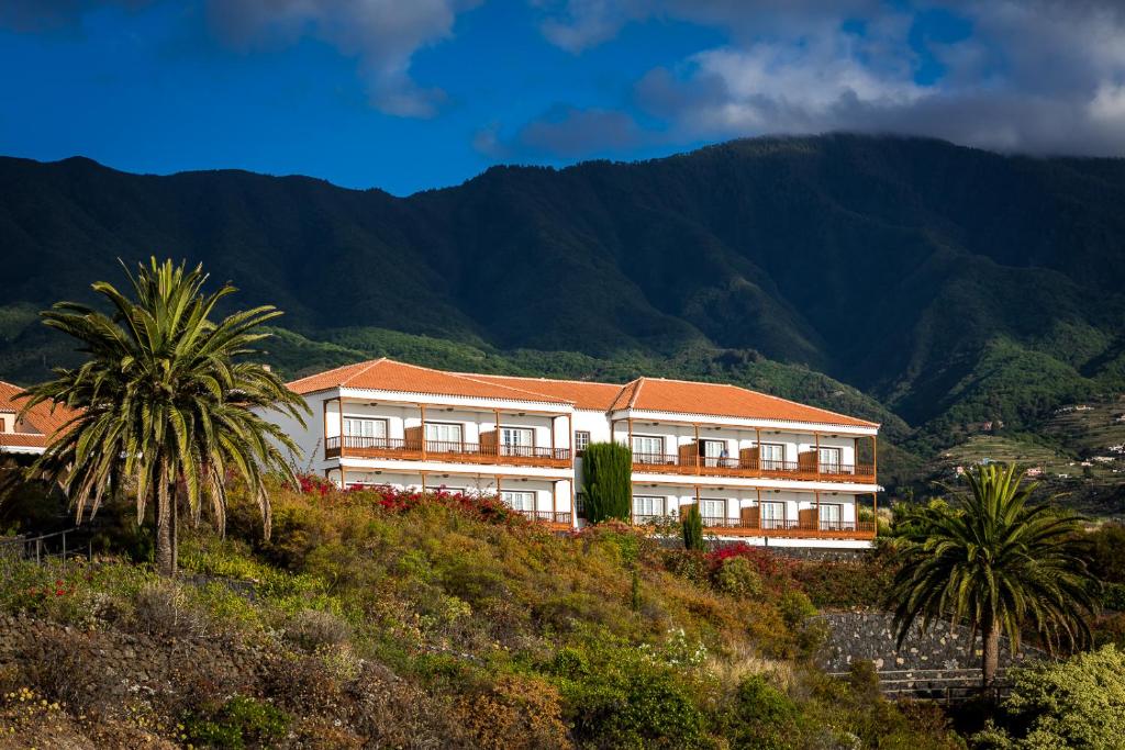 a building on a hill with palm trees and mountains at Parador de La Palma in Breña Baja