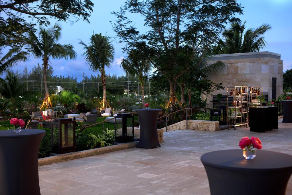 a patio with tables and chairs and palm trees at Kimpton Seafire Resort + Spa by IHG in West Bay