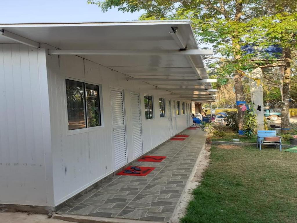 a white building with red chairs on the side of it at CAMPING RECANTO DOS PÁSSAROS in Chapada dos Guimarães