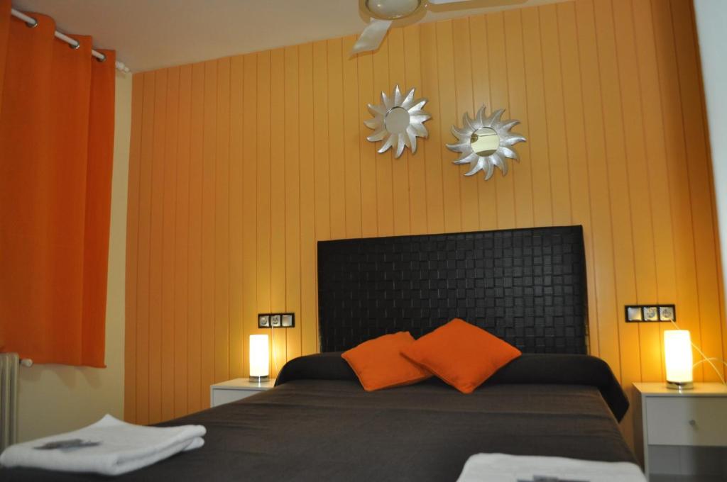 a bedroom with a bed with orange pillows and two mirrors at Hostal Empordà in Castelló d'Empúries