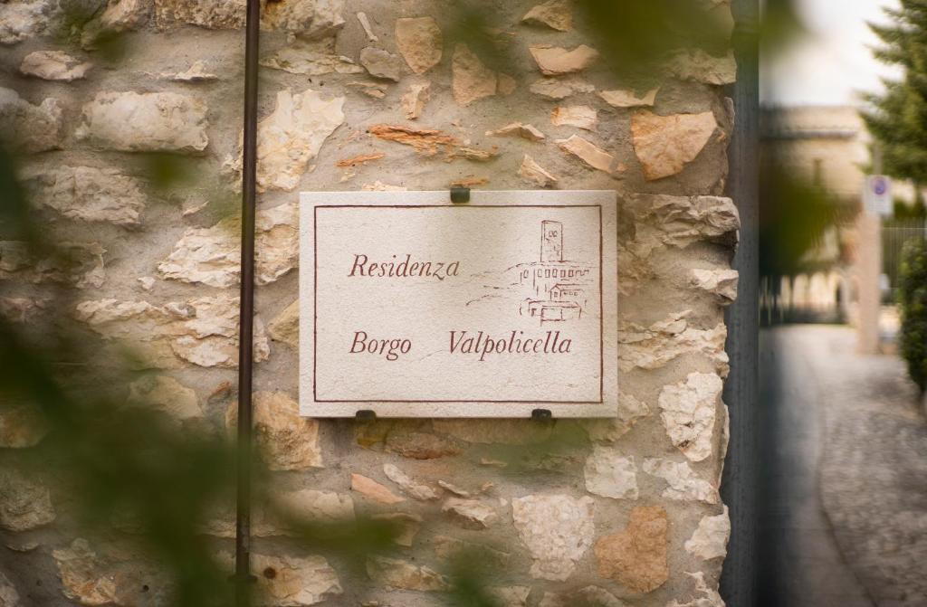 ein Schild an der Seite einer Steinmauer in der Unterkunft Residenza Borgo Valpolicella in SantʼAmbrogio di Valpolicella