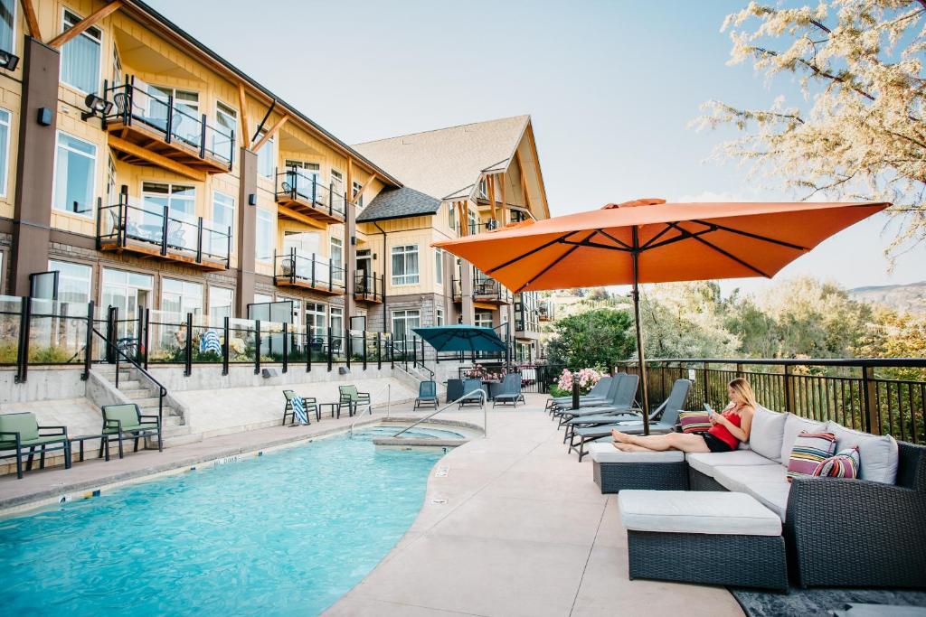 a patio area with a pool, chairs, and a patio umbrella at Summerland Waterfront Resort & Spa in Summerland
