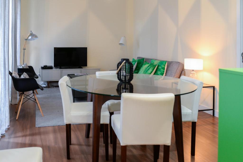 comedor con mesa de cristal y sillas blancas en Lisbon Apartment near Marquês Pombal square, en Lisboa