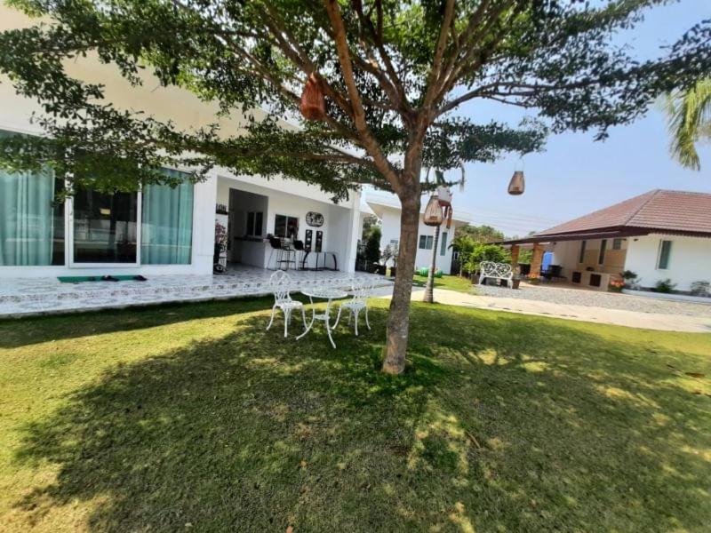 a table and chairs under a tree in a yard at Pon Resort in Ban Phe