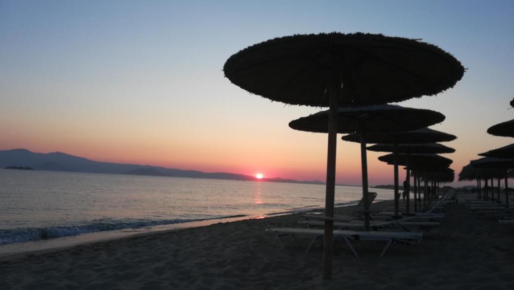 a group of umbrellas on the beach at sunset at Blue Harmony Apartments in Plaka