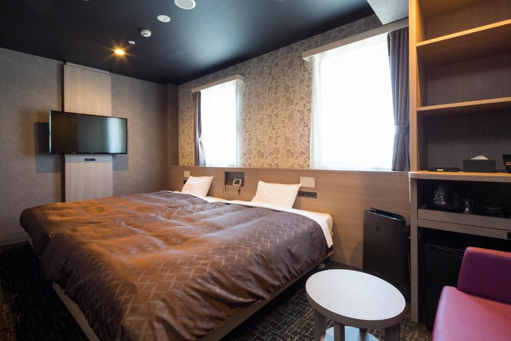 - une chambre avec un lit, une télévision et une table dans l'établissement Sanco Inn Nagoya - Shinkansenguchi, à Nagoya