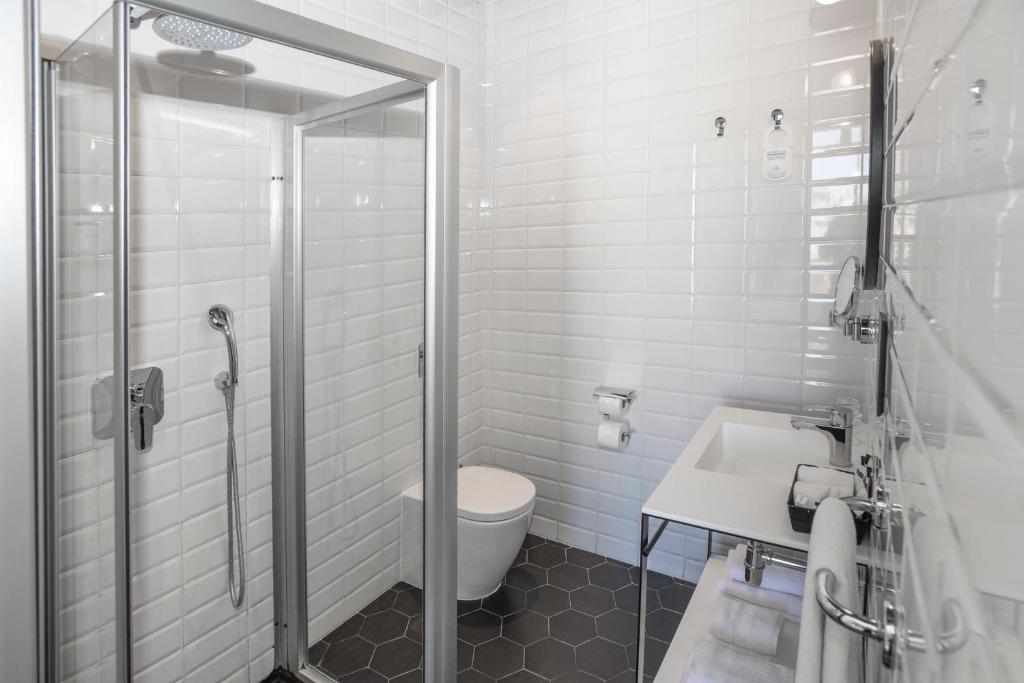 
a bathroom with a shower, toilet and sink at La Falconeria Hotel in Valletta
