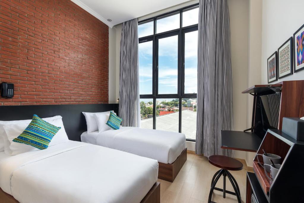 a hotel room with two beds and a window at S Loft Manado in Manado