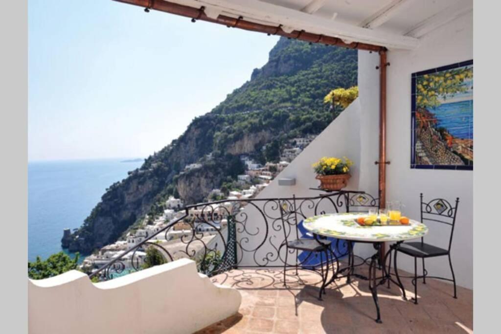 Un balcón con mesa y vista al mar. en Villa Profumo di Mare con vista mozzafiato, en Positano