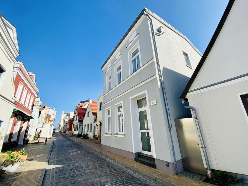 ein weißes Gebäude in einer Kopfsteinpflasterstraße in der Unterkunft Mole in Warnemünde