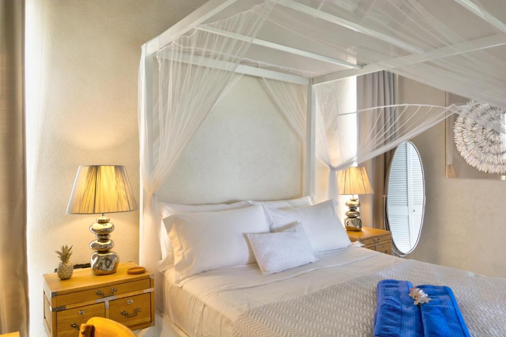 a bedroom with a white canopy bed and two lamps at West Rock Villas in Saint James