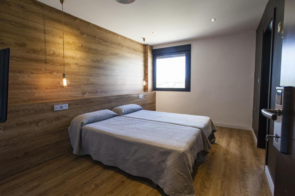a bedroom with a bed with a wooden wall at HOTEL ALCAZAR in Mula