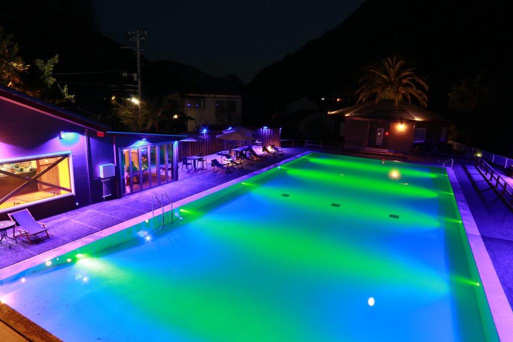 a swimming pool at night with green lights at Amis Droles in Kawazu