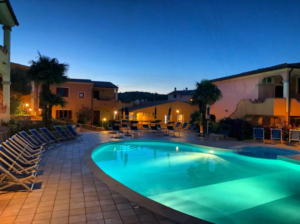 a swimming pool at night with chairs and a building at Residence Corte Dei Venti in Budoni
