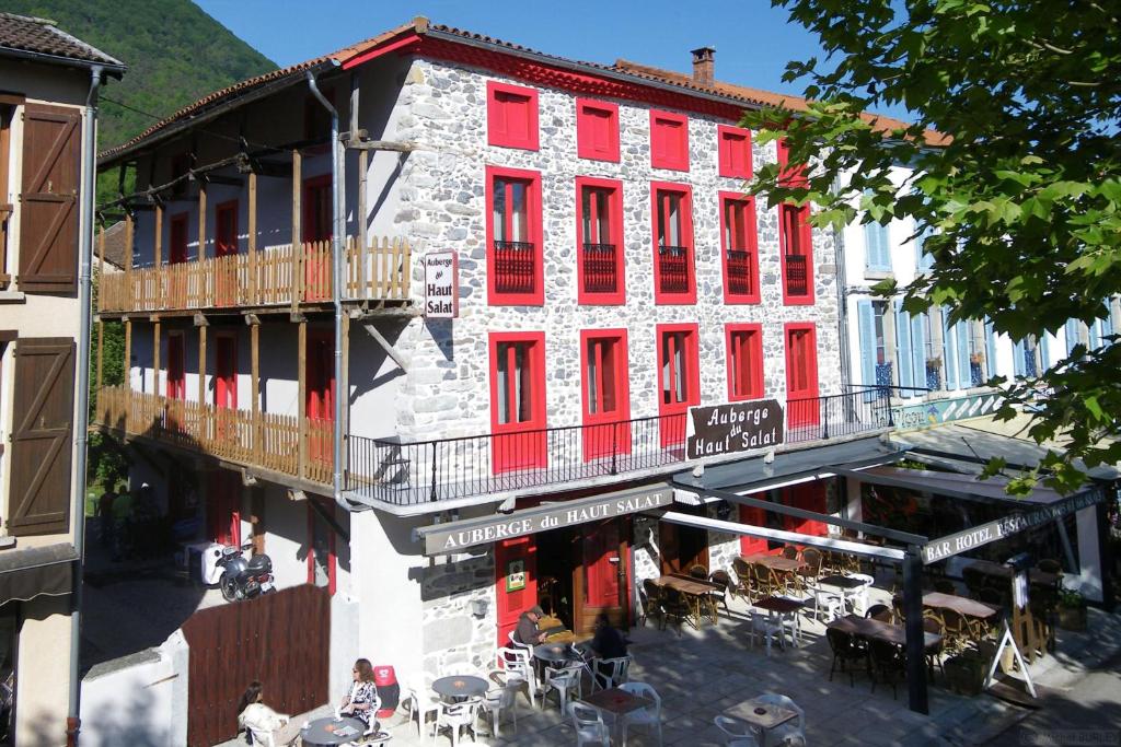 un edificio antiguo con ventanas rojas, mesas y sillas en Auberge du Haut Salat, en Seix
