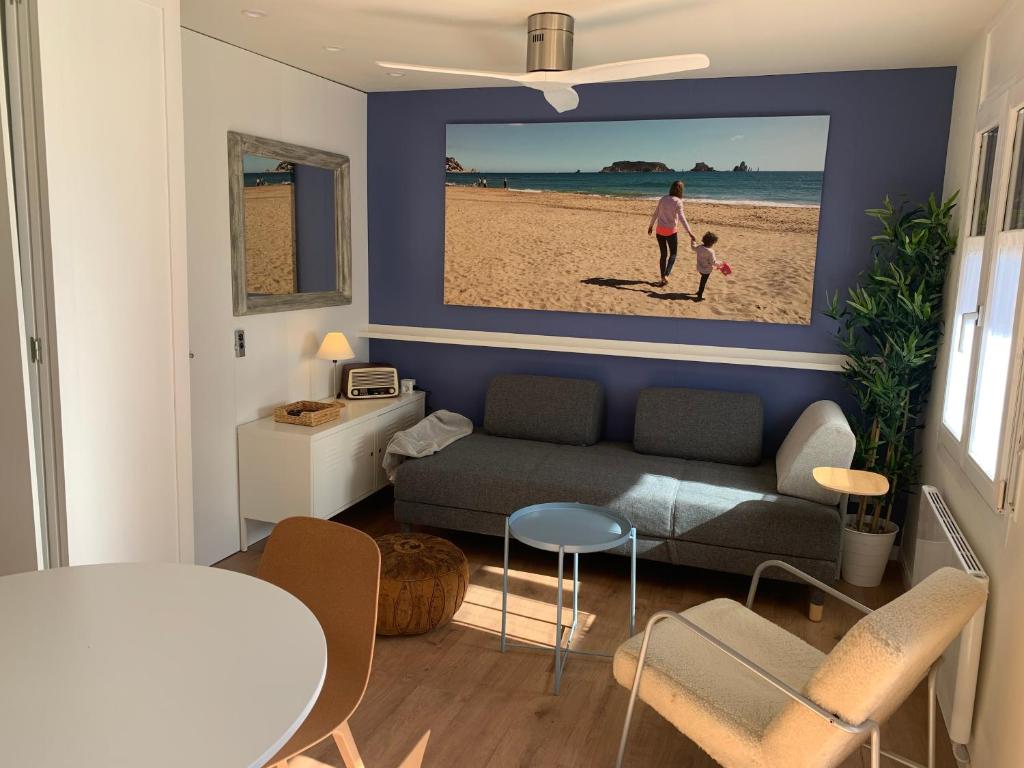 una sala de estar con sofá y una foto de la playa en Mas PineII 2 - Viu Bé, en Torroella de Montgrí