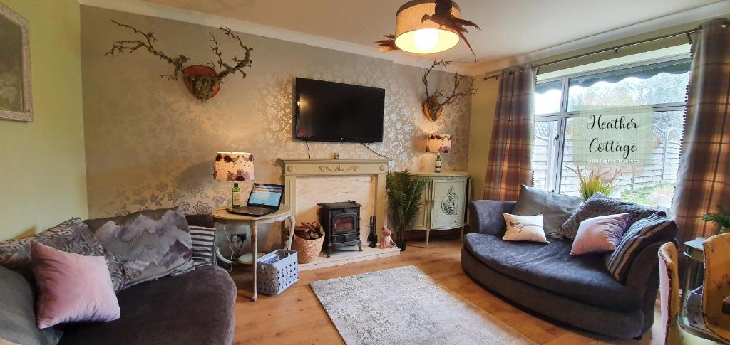 a living room with two couches and a fireplace at Heather Cottage Aberdeen in Aberdeen