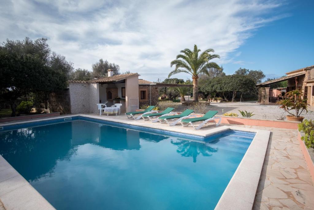 a swimming pool with chairs and a house at Sa Bassa Llova mit Pool und Wifi in Santanyi