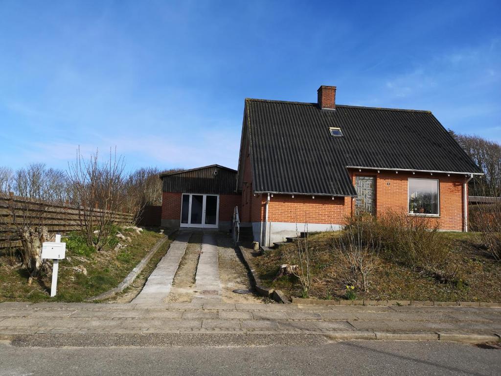 a brick house with a black roof at Logi i hus med kunst og have in Vestervig