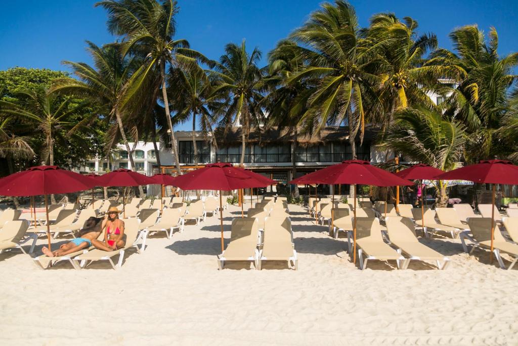 un grupo de sillas y sombrillas en una playa en Kinta Kan Beach Hotel Boutique Playa del Carmen en Playa del Carmen