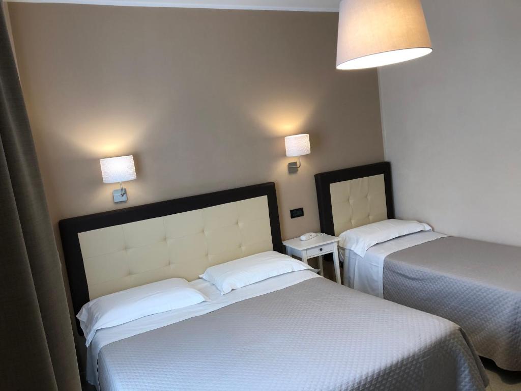 a hotel room with two beds and two lamps at Hotel Di Stefano in Pisa