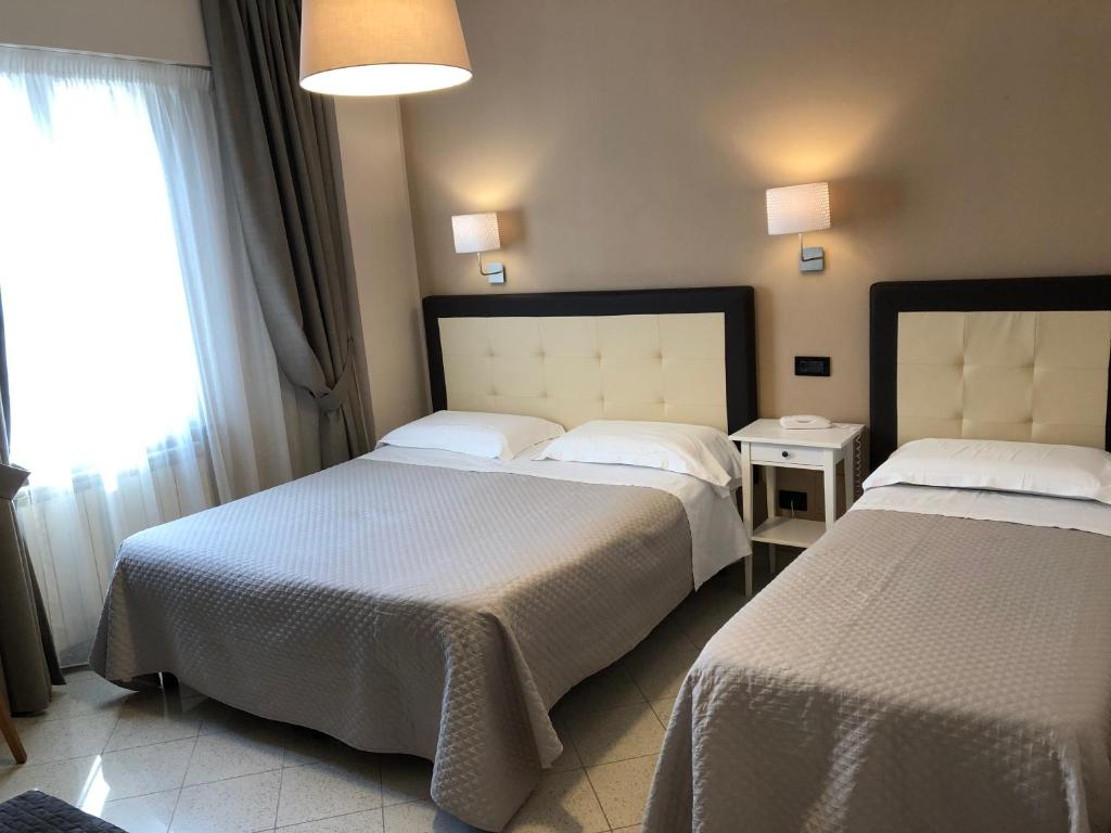 a hotel room with two beds and a window at Hotel Di Stefano in Pisa