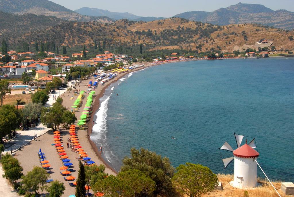 a beach with chairs and umbrellas and a lighthouse at Grand Blue Villa Michaella 2 in Anaxos