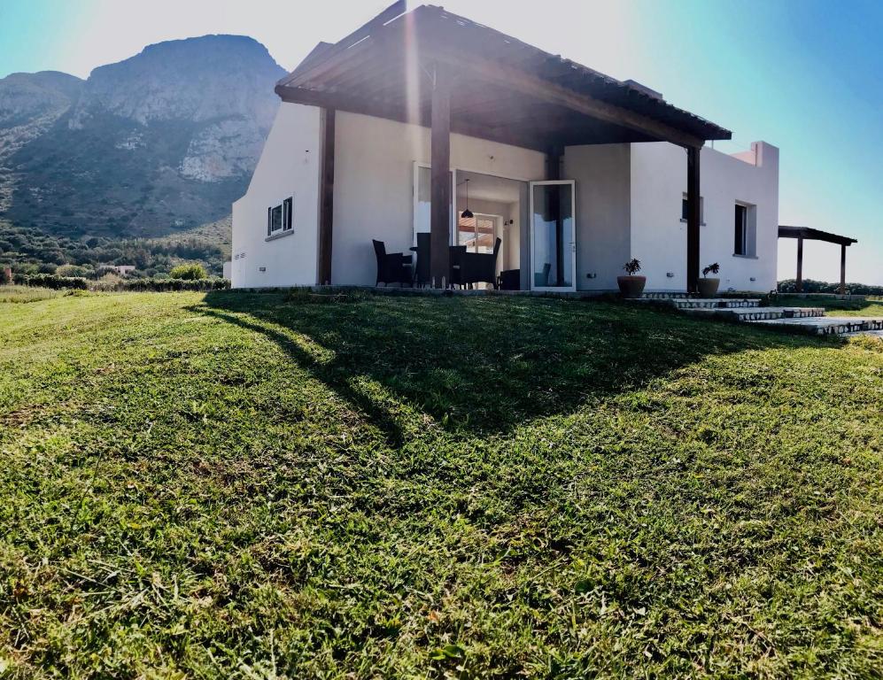 a white house on a grassy field with a mountain at Casa Vigna in Favignana