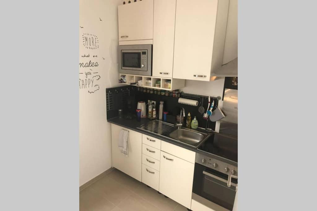 a kitchen with white cabinets and a sink and a microwave at Central, Modern, mit großem Balkon Checkin123 in Wiesbaden