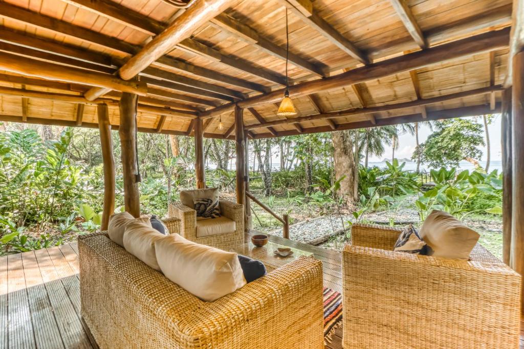 a porch with wicker furniture and a wooden ceiling at El Ballenato de Bahia #2 in Uvita
