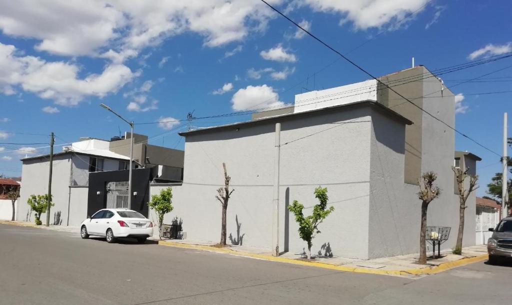 a white building with a car parked in front of it at VIRREYES418 extended apartments in Los Valdeses