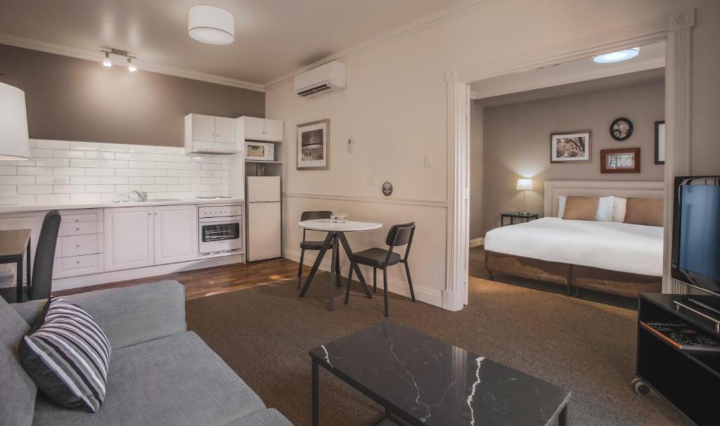 a living room with a bed and a room with a couch at Majestic Old Lion Apartments in Adelaide