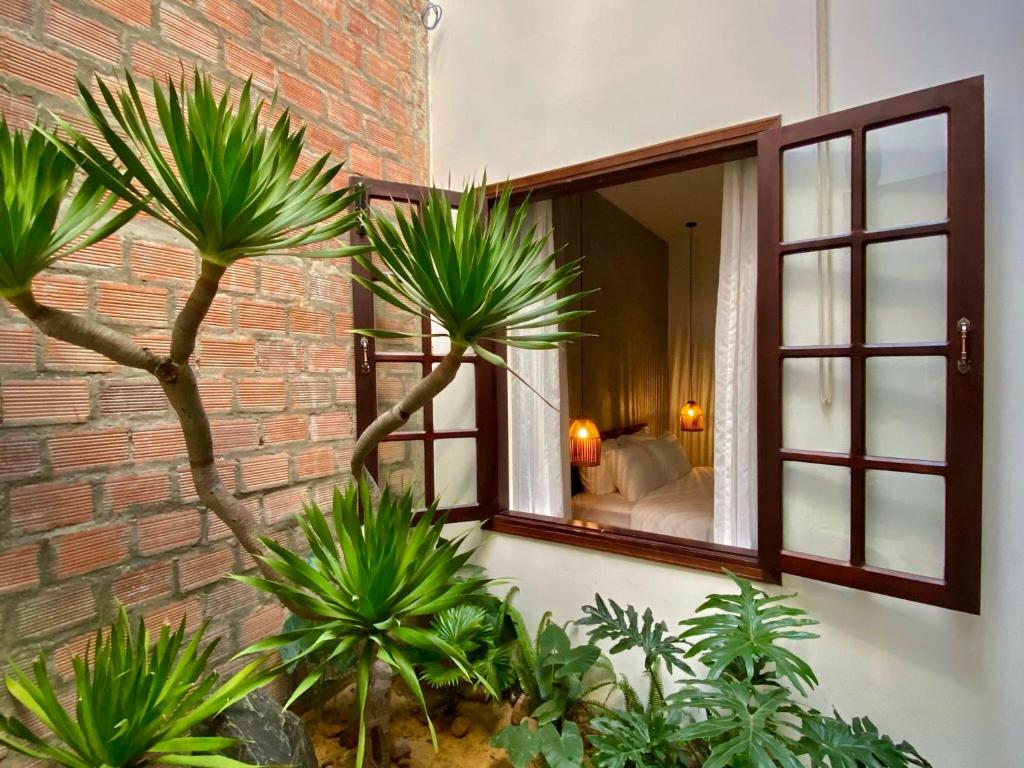 a room with a window with palm trees and a bedroom at Okra Hoian in Hoi An