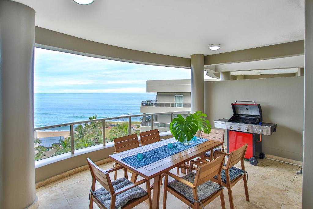 a dining room with a table and chairs and the ocean at 504 Ballito Manor View-Luxury home on the main beach in Ballito