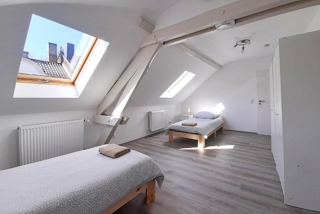 a attic bedroom with two beds and two windows at Work & Stay Apartment in Stolberg bei Aachen in Stolberg