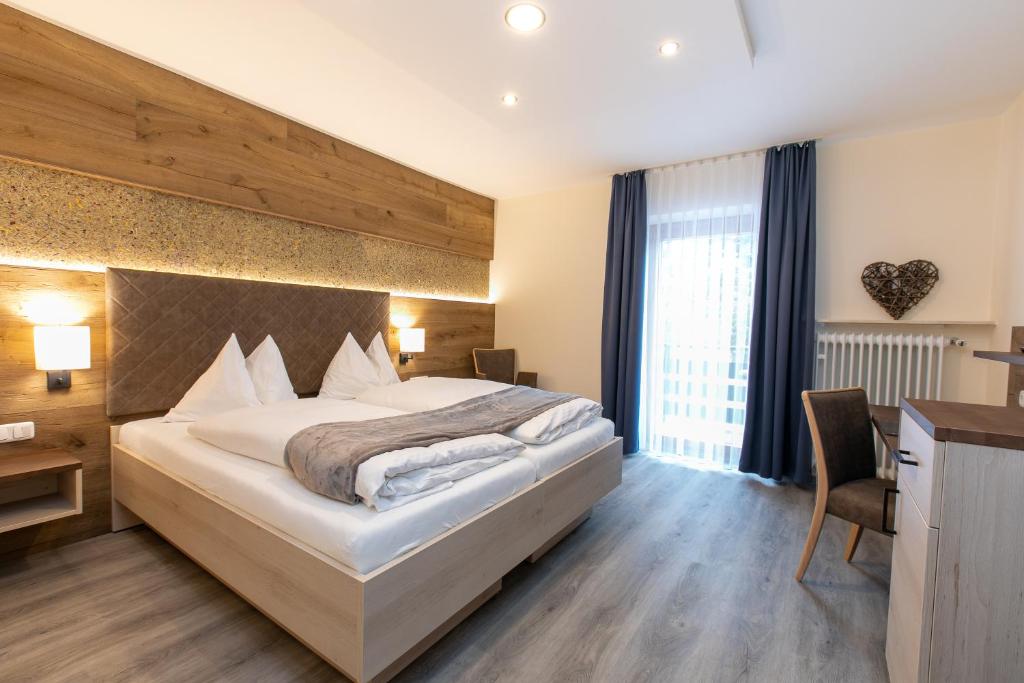 バート・テルツにあるHotel am Waldの大きなベッドとデスクが備わるホテルルームです。