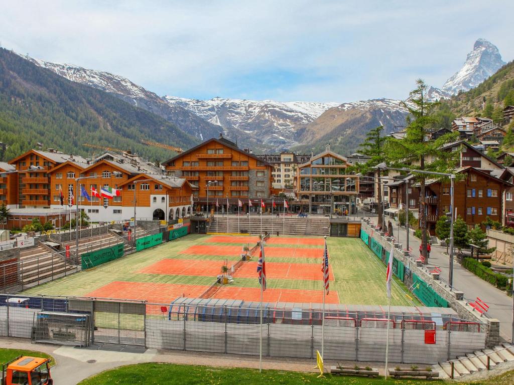 a tennis court in the middle of a town with mountains at Apartment Haus Whymper Edward Suite by Interhome in Zermatt